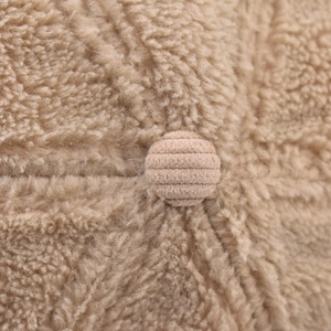 Close-up of khaki corduroy covered button on fuzzy lamb wool winter baseball cap texture