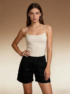Dettaglio del top beige a coste e pantaloncini neri in twill sul modello