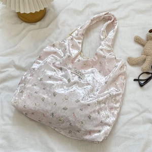 Close-up of pink pearlescent silk shoulder bag with bear and bow print texture