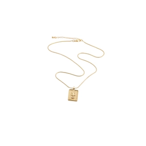 Macro detail of a gold-plated rectangular pendant with abstract relief on a snake chain