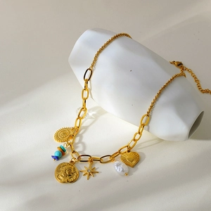 Detail of vintage gold necklace with pearl, heart, and coin pendants on ceramic stand