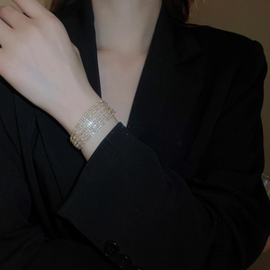 Close-up of a multi-layer gold-tone bracelet with sparkling crystals on a model wrist