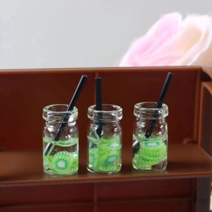 Detailed close-up of miniature kiwi juice bottles with realistic fruit slices and black straws