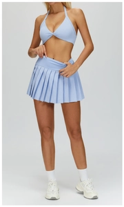 Close-up of light blue halter neck sports bra with twist front and pleated mini skirt
