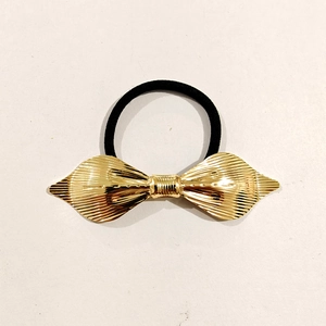 Detailed top view of a gold metallic flower hair tie with a black elastic band on white background