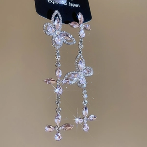Detail of silver drop earrings featuring pink crystal butterflies and long tassel fringe