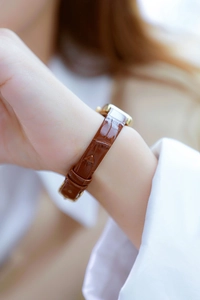 Close-up of brown crocodile pattern leather strap on a gold luxury women's wrist watch