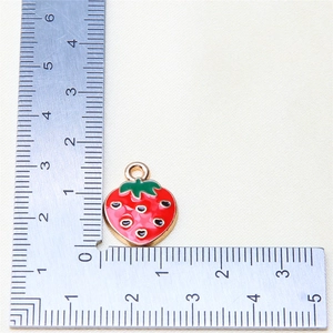 Detailed strawberry pendant charm size measurement on white fabric with a ruler