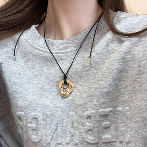 Close-up of molten style gold heart pendant on a minimalist black cord necklace