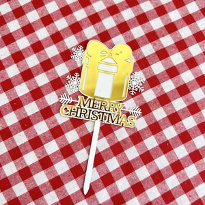 Detailed view of golden acrylic Merry Christmas cake topper with gift and snowflake designs