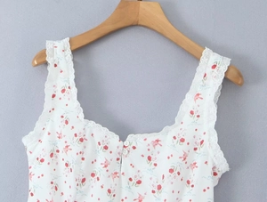 Detalle de la blusa blanca de flores con ribete de encaje y botones frontales finos