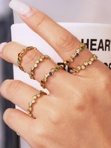 Close-up of gold rings set with colorful zircons and bezel settings on fingers