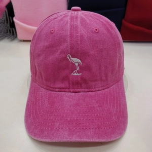 Detail of rose red washed baseball cap with white bird embroidery and premium stitching