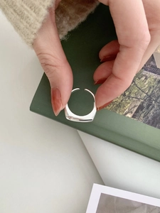Close-up of a minimalist silver square ring worn on hand with an adjustable open band design