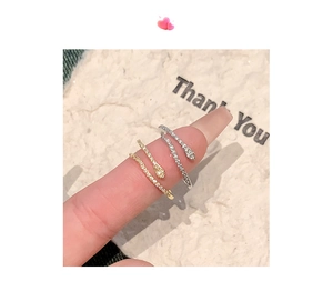 Detail of adjustable snake ring in gold and silver finish with zircon inlay on finger