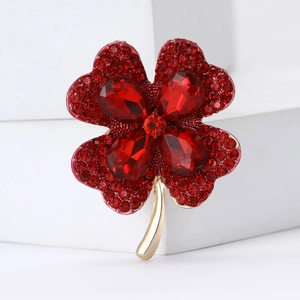 Elegant gold four-leaf clover brooch featuring sparkling red rhinestones and crystals