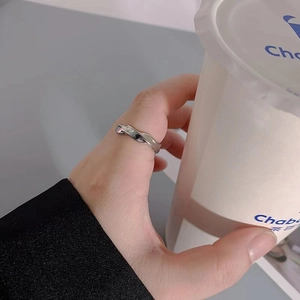 Detail of silver Mobius steel ring worn on hand while holding a white paper cup