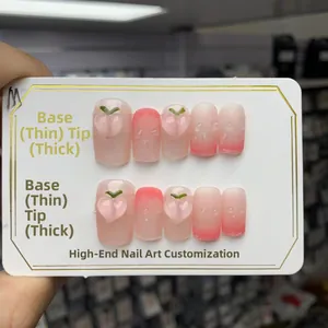 Vue détaillée des faux ongles dégradés roses avec pêches 3D et textures gouttes d'eau