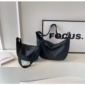 Size comparison of large and small black nylon crescent crossbody bags in matte finish