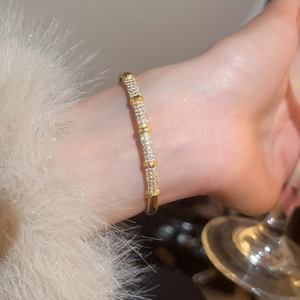 Detail of gold plated bamboo bangle with white cubic zirconia worn on a female wrist