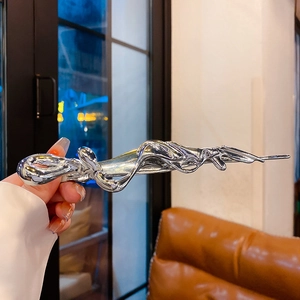 Detail of silver liquid metal butterfly hair clip held against a blurred night city background