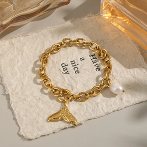 Détail d'un bracelet en chaîne dorée avec perle d'eau douce et pendentif queue de poisson