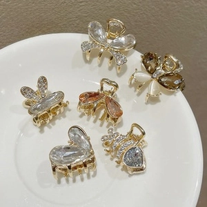 Close-up of a 6-piece mini gold hair claw set with rhinestones and floral bow designs