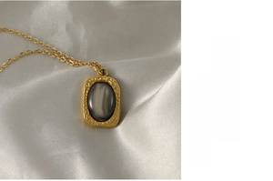 Macro shot of tiger eye stone pendant with hammered gold texture on white silk fabric