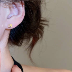 Close-up of minimalist gold square cube stud earrings worn for a modern daily look