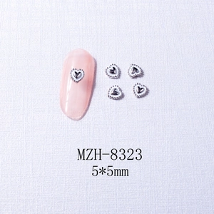 Detailed view of silver heart nail charms 5x5mm shown on white textured fabric