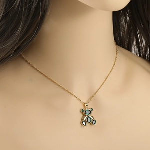 Elegant gold bear pendant necklace with green zircon gemstone worn on model's neck