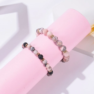 Detail of pink zebra stone and black lava rock beaded bracelets on a display stand