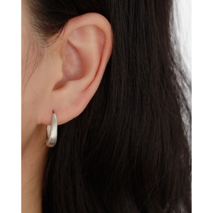Close-up of a minimalist s925 silver earring with brushed metal texture on a female model