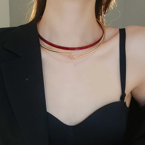 Detail of a minimalist gold metal ring and deep red resin double-layered necklace