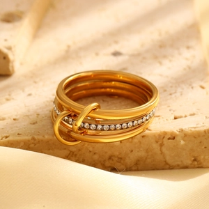 Detail of gold multilayer ring with sparkling cubic zirconia and small circle pendant