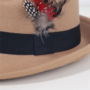 Dettaglio del cappello in feltro di lana con nastro nero e decorazione piumata