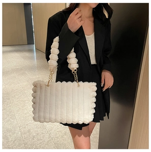 Detail of white plush tote bag with vertical stripes and golden chain strap
