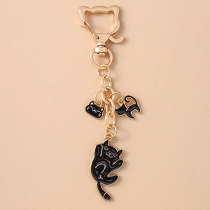 Detail of gold keychain featuring black enamel cat charms and feline-shaped spring clip
