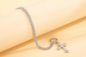 Detail of silver cross pendant with rose carving and sparkling crystals on double chain