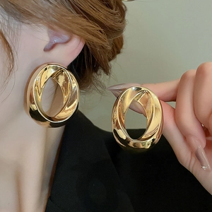 Golden twisted oval hoop earrings for women featuring a stylish hollowed-out metal design