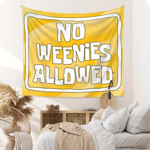 Detail of yellow wall tapestry with 'NO WEENIES ALLOWED' slogan in a cozy bedroom setup