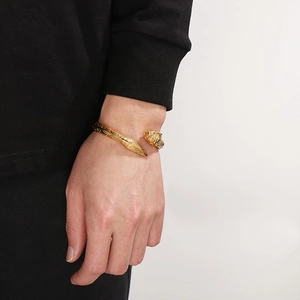 Detailed view of a gold tiger head open bangle bracelet on a male model wrist