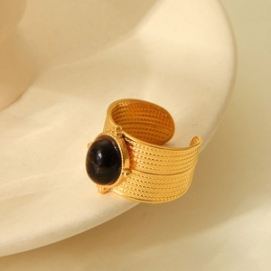 Detail of 18K gold-plated wide ring with oval black stone on artistic ceramic dish