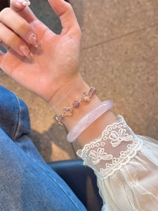 Gros plan d'un bracelet jonc rose et d'un bracelet en cristal violet avec fleurs