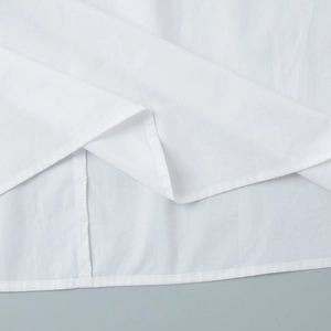 Detailed close-up of white shirt hem featuring precise double-needle stitching and fabric texture