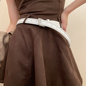 Close-up of a white vintage leather belt with silver rivets on a brown suede dress