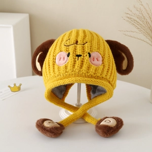 Detailed view of yellow knit dog hat with plush lining and decorative pom-poms for kids