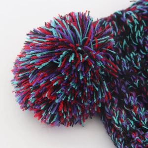 Detailed macro shot of a fluffy colorful knit pom-pom featuring red, teal, and purple yarn