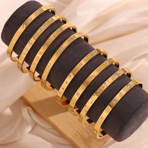 Detail of 18K gold plated bracelets with sea motifs and small diamond accents on stand