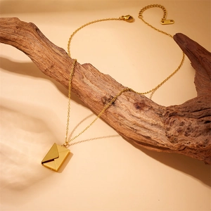 Gold-plated stainless steel envelope pendant necklace hanging on a wooden branch